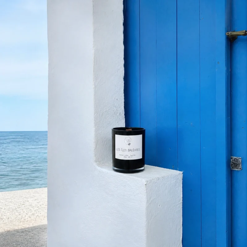 Imagen de vela aromatica Les Iles Baleares frente a puerta azul de la cala del Portixol en Javea